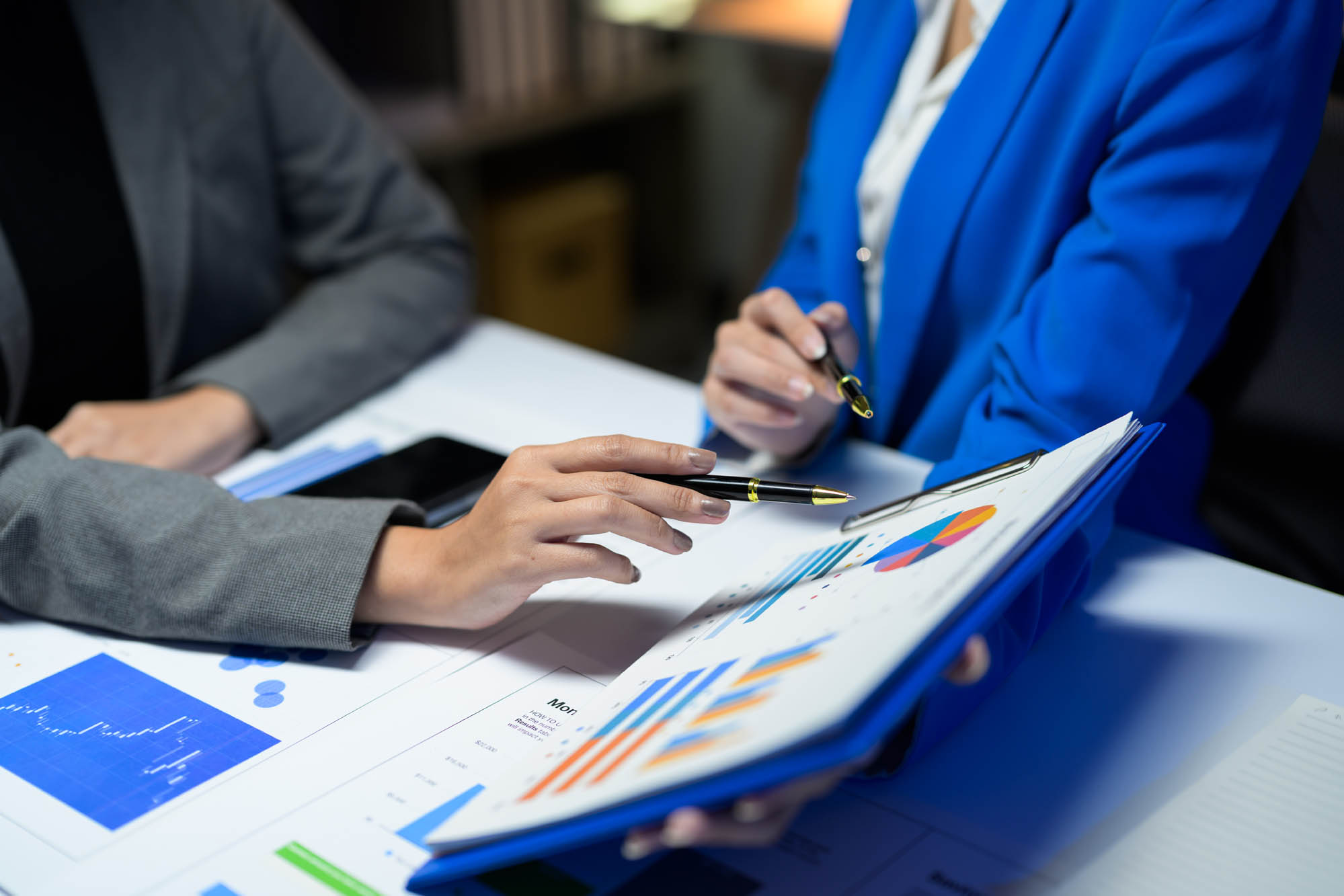 K&W Marketing Consultants | Businesswomen analyzing financial charts and graphs discussing company strategy